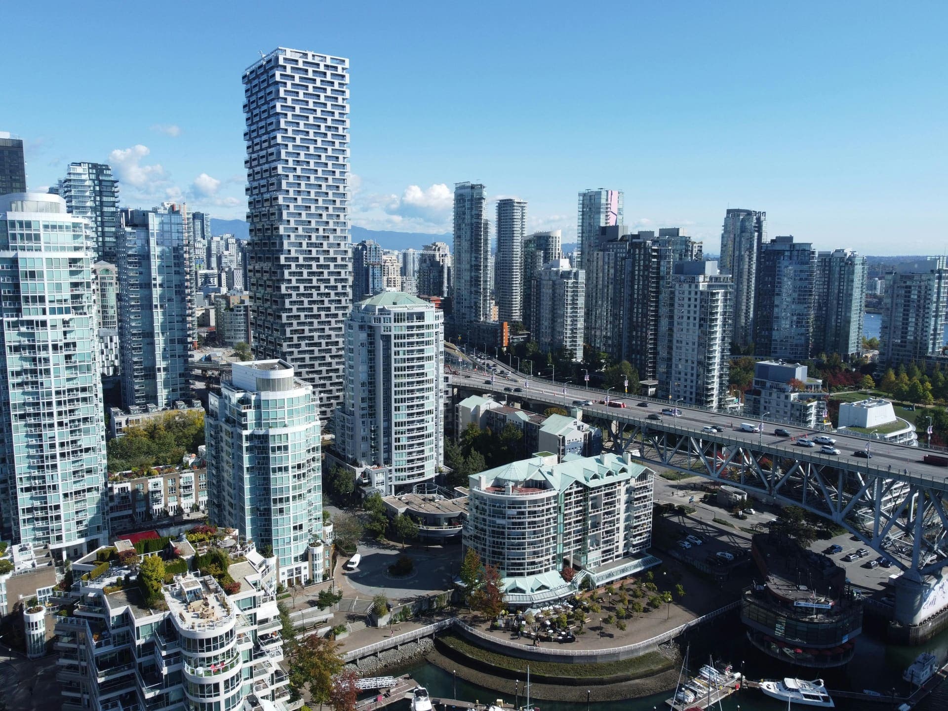Greater Vancouver downtown skyline — modern condo towers along Burrard Inlet with North Shore mountains.